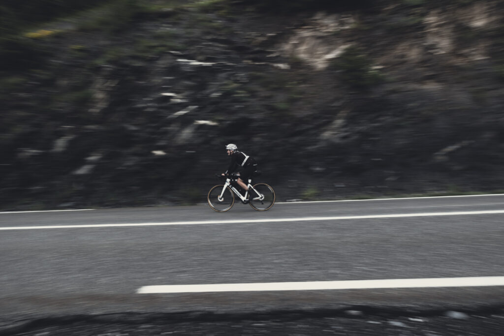 man alone on his bike on the road in the mountains