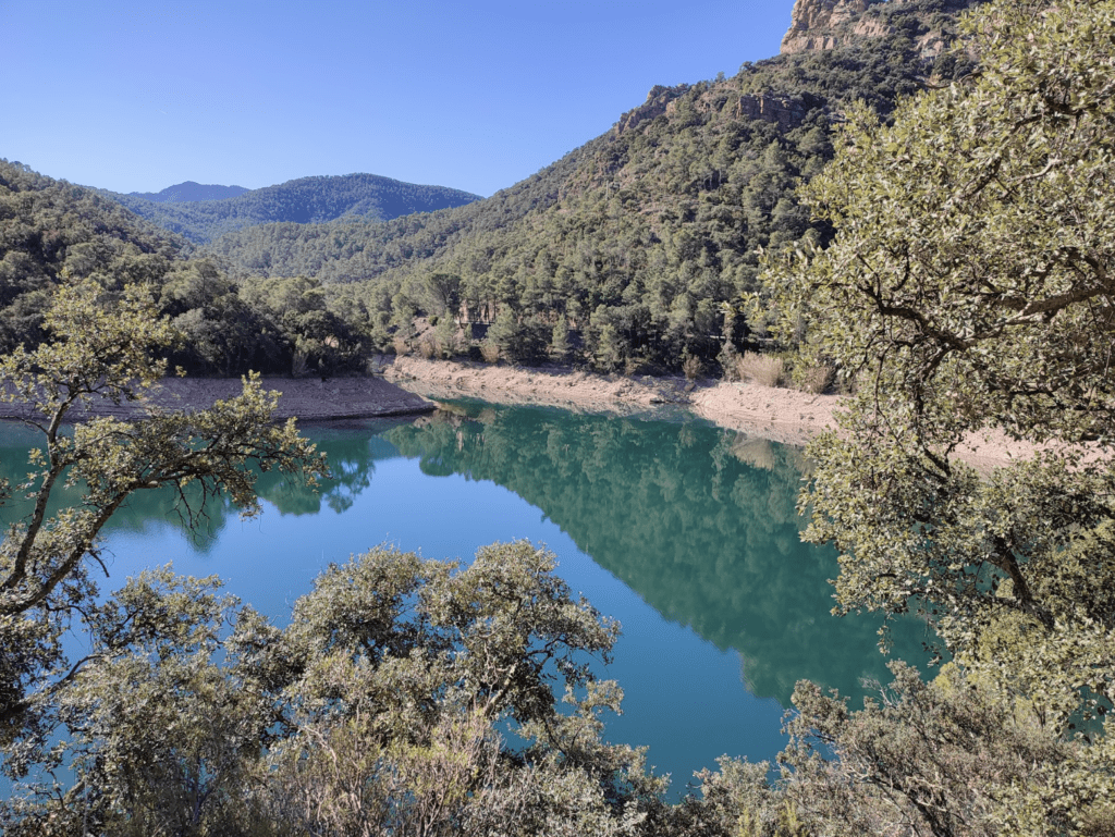 Vue sur le parc naturel de Sierra de Espadan, on voit un lac avec des arbes, des montagnes, un ciel bleu